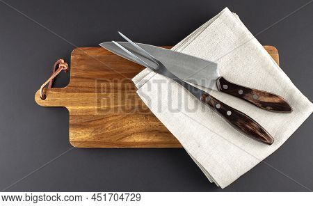 Wooden Cutting Board And Fork And Knife Carving Set On A Black Background