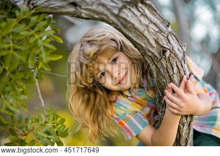 Cute Little Kid Boy Enjoying Climbing On Tree On Summer Day. Kid Happily Lying In A Tree Hugging A B