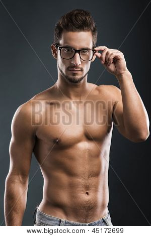 Nackter Oberkörper männliches Model posiert mit Brille über einen blauen Hintergrund