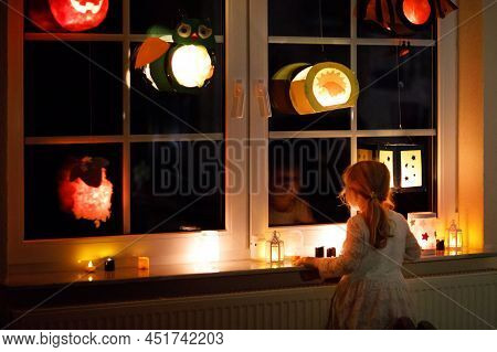 Little Kid Girl Sitting By Window With Selfmade Hand Crafted Lanterns With Candles For St. Martin Pr