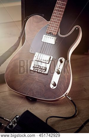 Close Up On The Body Of Custom Electric Guitar With Natural Finish, It's Leaned Against Amp, Pedal O