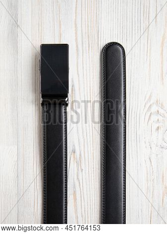 End Parts Of Black Fashionable Men's Leather Belt With Automatic Buckle On White Wood Background. Ma