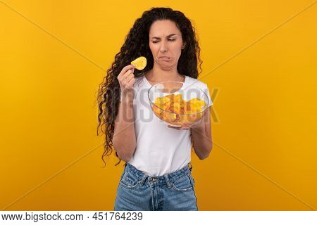 Confused Young Lady Eating Unsavory Potato Crisps