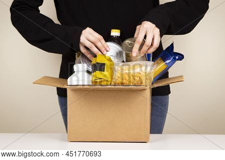 Volunteer Hands Collecting Food Into Donation Box. Cardbox Full Of Grocery Products. Donation, Chari