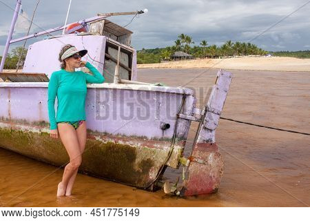 Lady Posing Next To An Old Abandon And Half Sunken Old Fishing Boat At Praia Dos Nativos, In Trancos