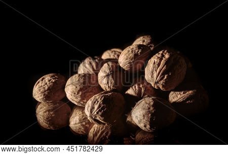 A Walnuts Heap Close-up. Copy Space. Beautiful Still Life On A Dark Background. Healthy Food. Ingred