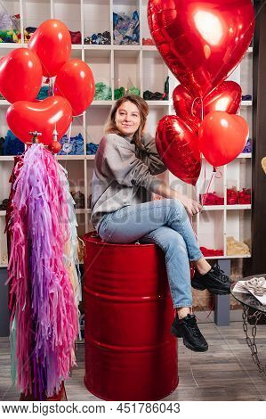 Woman On Red Decorative Barrel. With A Large Red Balloons In The Shape Of Heart.