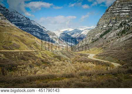 A Road Running Through A Valley Surrounded By Mountains