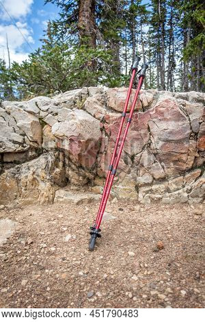 Two Red Trekking Poles Leaning On A Rock In The Mountains