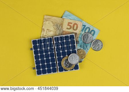 Photovoltaic Panel , Money And Plug Wire Isolated On Yellow Background. Olar Panel With Varied Value