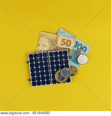 Photovoltaic Panel , Money And Plug Wire Isolated On Yellow Background. Olar Panel With Varied Value