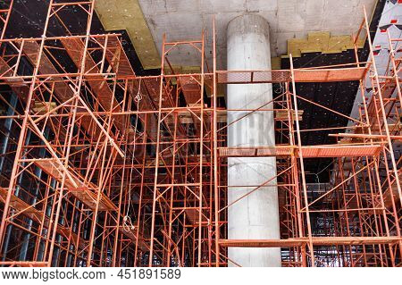 Metal Scaffolding In The Process Of Insulating The Facade Of A New Building Surrounds A Reinforced C
