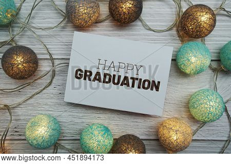 Happy Graduation Text On Paper Card With Led Cotton Balls Top View On Wooden Background