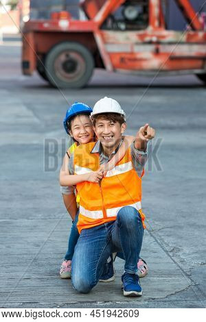 Father And Little Daughter Wearing A Safety Helmet At Container Cargo Site. Business Heir Concept. H