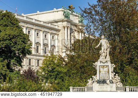 Wolfgang Amadeus Mozart Statue In Burggarten Park With Hofburg Palace At Background, Vienna, Austria