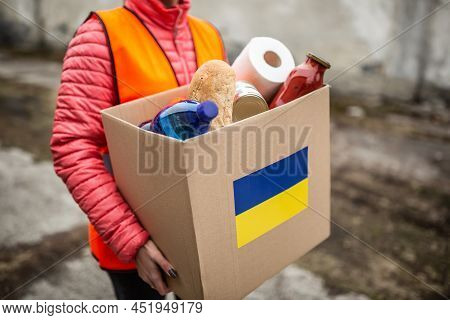 Ngo Volunteer Carries A Box With Basic Food And Toilet Papier With A Ukrianian Flag Sticker On The C