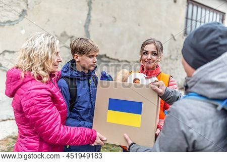 Woman With Two Teenagers Accepts A Box Of Humaitarian Aid For Ukrainians In The War Affected Zone.