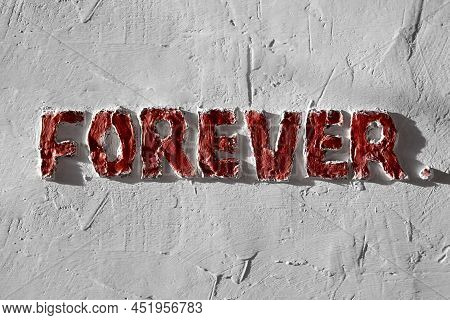 The Inscription Forever Made In Bas-relief On A Concrete Plastered Wall. Red Paint On Gray Concrete.