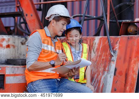 Man Engineering And Daughters Sitting On Forklift Working With Clipboard In Container Yard. Work Edu