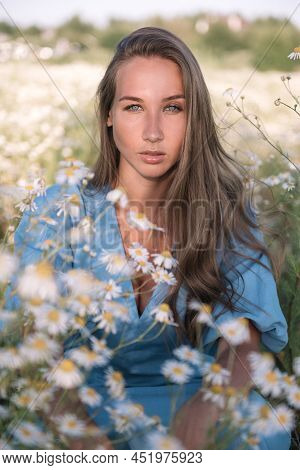 A Beautiful Woman In A Blue Dress Is In The Chamomile Field