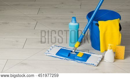 Blue Cleaning Accessories And A Yellow Rag On The Wooden Floor. Home And Office Cleaning Kit. The Co