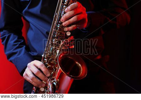 Man With Saxophone On Dark Background, Closeup