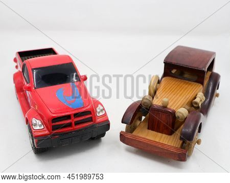 Miniature Toy Models Of A Red Tow Truck And A Brown Wooden Vintage Car Isolated In A White Backgroun