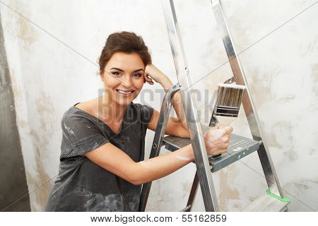 Happy beautiful young woman doing wall painting
