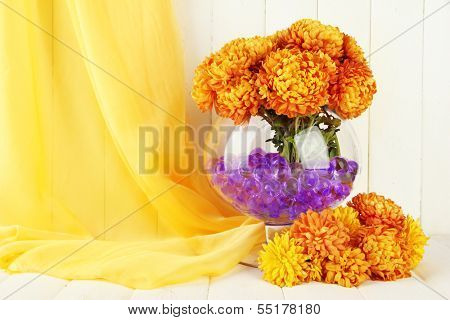 Beautiful flowers in vase with hydrogel on table on wooden background