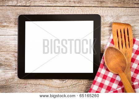 Tablet On Wooden Surface And Serving Spoons.