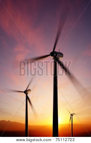 Wind Turbine blades spinning at close range with golden sunset. Focused on tip of front blade