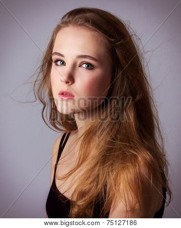 young, beautiful girl in a black t-shirt. Professional model posing in Studio on white-gray