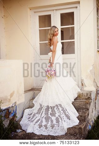 Blonde bride with veil by old house