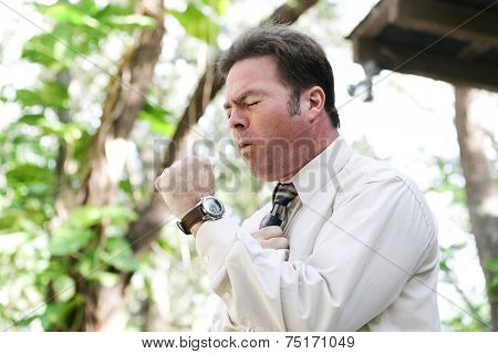 Businessman coughing from the flu, a cold, or other illness, in outdoor environment.  