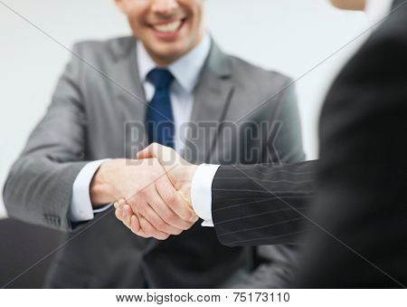 businesss and office concept - two businessmen shaking hands in office