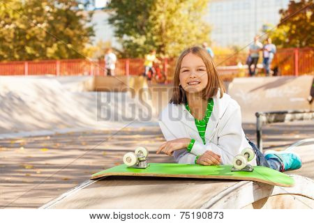 Girl lays near green skateboard with wheels up