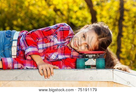 Beautiful girl laying with head on skateboard