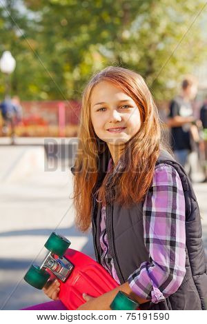 Cute smiling girl with long hair and skateboard