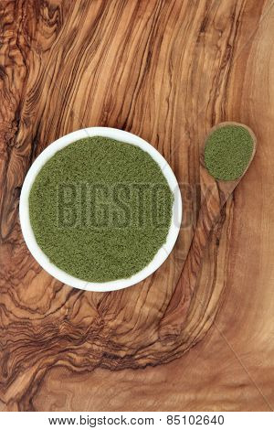 Gurmar powder super food used in ayurveda alternative medicine for weight loss as an appetite suppressant over olive wood background. Gymnema sylvestre