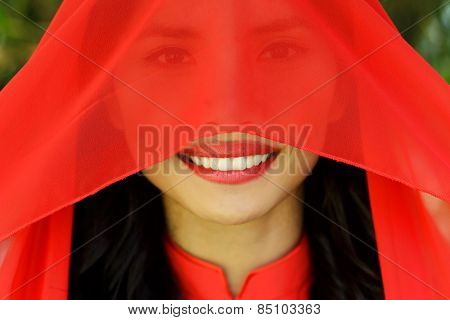 Close up Happy Young Asian Woman with Red Scarf Covering her Face, Looking at the Camera with a Smile