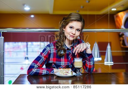 Young Beautiful Girl Sitting In A Cafe With A Cup Of Mokachino And Cake