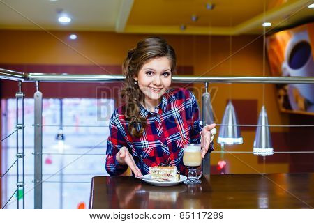 Nice Smiling Girl Sitting In A Cafe With A Cup Of Mokachino And Cake