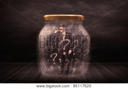 Businessman locked into a jar with question marks concept on background