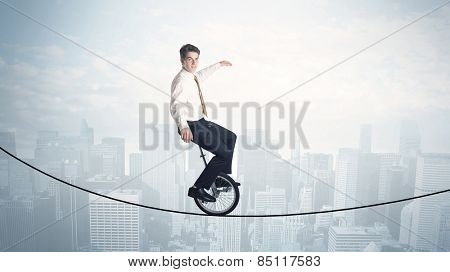 Brave guy riding a monocycle on a rope above cityscape concept