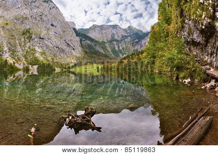 Magic reflection in German lake Koenigssee. Clouds and mountains reflected in the mirrored surface of the water. Cloudy day on the lake