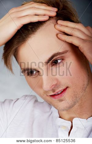 Young handsome man is worried about hair loss.