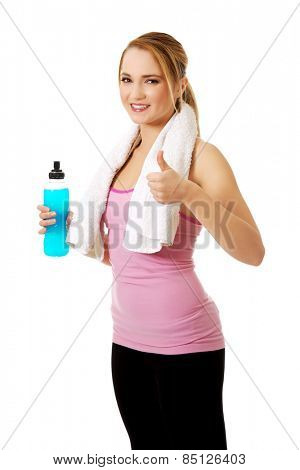 Attractive woman in fitness clothes with isotonic drink and ok sign.