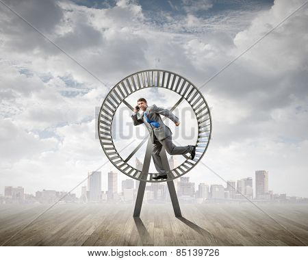 Young businessman running in huge hamster wheel