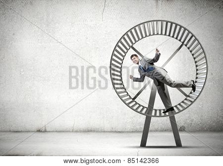 Young businessman running in huge hamster wheel