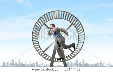 Young businessman running in huge hamster wheel